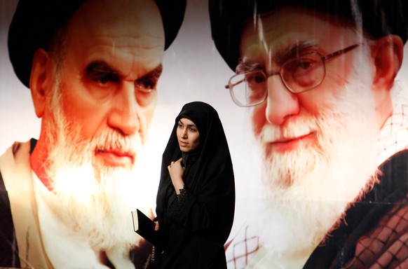 epaselect epa04598311 An Iranian woman passes in front of a huge poster of the late supreme leader of the 1979 Islamic Revolution, Grand Ayatollah Ruhollah Khomeini (L) and Iranian supreme leader Ayat ...