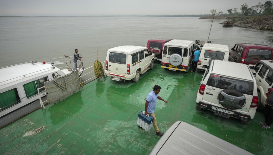 An election official walks carrying an electronic voting machine (EVM) as he prepares to disembark from a ferry after crossing the river Brahmaputra on the eve of the first phase of polling of India&# ...