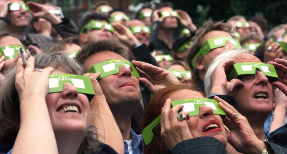 Mit Spezialbrillen geschuetzt betrachten Schaulustige am 11. Aug. 1999 in Hamburg eine totale Sonnenfinsternis. (KEYSTONE/AP Photo/Christof Stache)