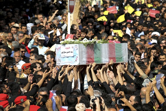 Mourners carry a casket during a mass funeral for those who died in a terror attack on a military parade in the southwestern city of Ahvaz, that killed 25 people attend a mass funeral ceremony, in Ahv ...