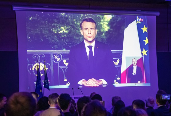 epa11400832 Supporters of presidential party RE Renaissance watch French President Emmanuel Macron?s speech displayed on the screen at the electoral party after the announcement of the results in Pari ...