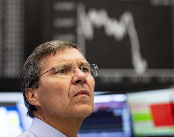 A broker watches his screens with the German stock index DAX in background at the stock market in Frankfurt, Germany, Thursday, Aug. 15, 2019. (AP Photo/Michael Probst)