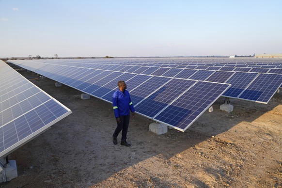 A man walks through a solar farm on the outskirts of Harare, Zimbabwe on Wednesday, Aug. 24, 2022. Access to more and cleaner energy while continuing to grow economically will be a top priority for Af ...