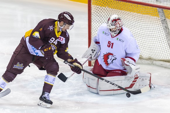 Le gardien du club lausannois, Tobias Stephan, droite, a la lutte pour le puck avec le joueur du club genevois, Tim Bozon, gauche, lors du match du championnat suisse de hockey sur glace de National L ...