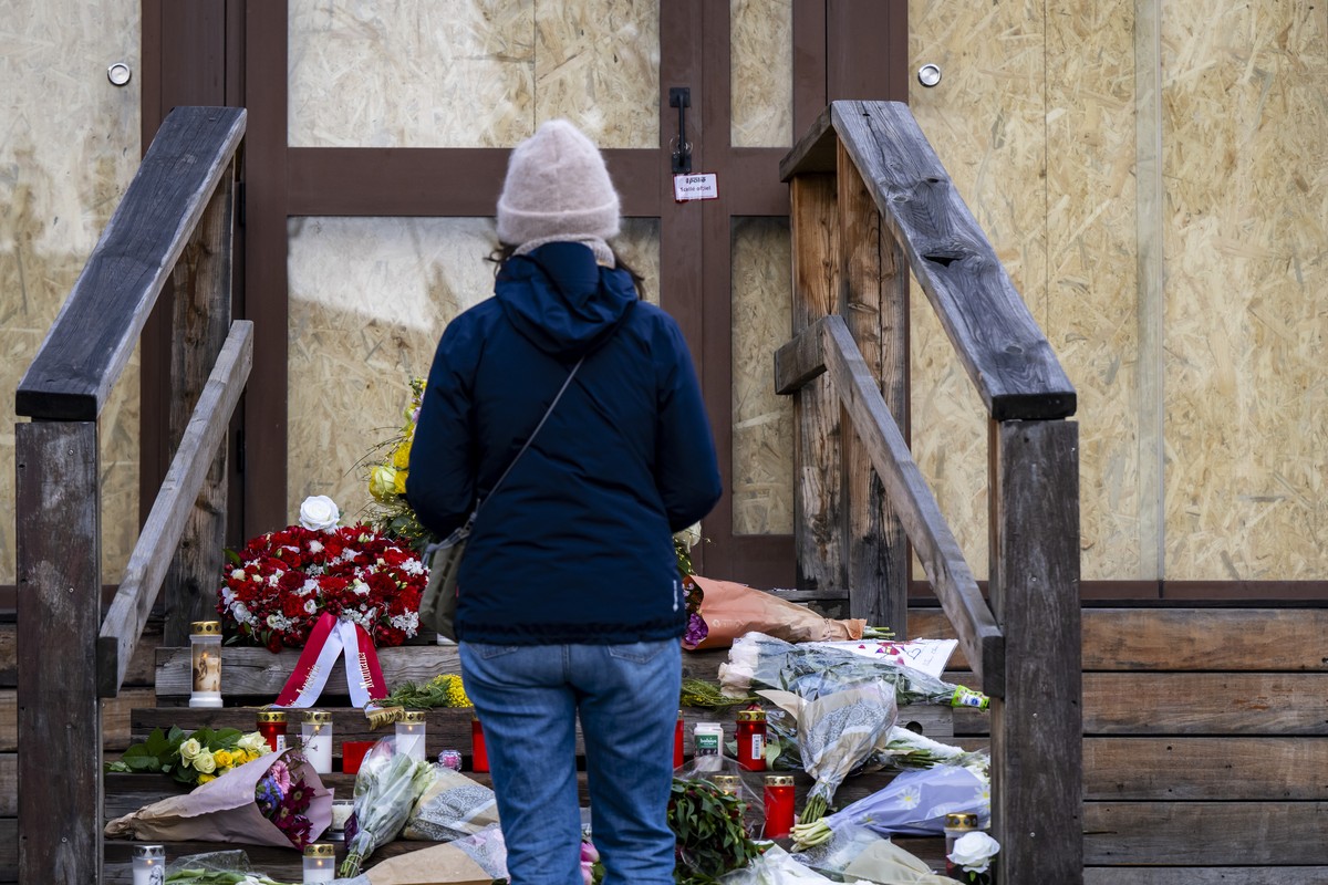 epa12693042 Flowers and candles are left in tribute to the victims in front of the entrance of the Le Constellation bar in Crans-Montana, Switzerland, 30 January 2026. Dozens of people, mostly teenage ...