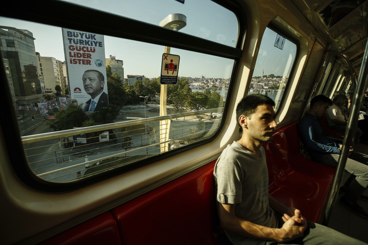 Commuters on a metro carriage pass a poster of Turkey's President Recep Tayyip Erdogan, in Istanbul, Friday, June 15, 2018. Turkey holds parliamentary and presidential elections on June 24, 2018, ...