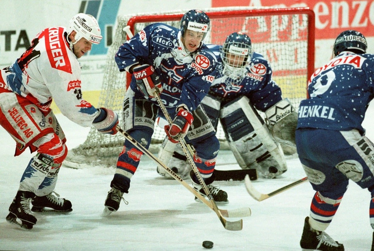 Chad Silver (links) von Herisau und Marco Kloeti (Mitte) vom EHC Kloten stochern am Samstag, 24. Januar 1998, im Spiel Herisau-Kloten in Herisau nach dem Puck, beobachtet von den Klotenern Matthias Sc ...