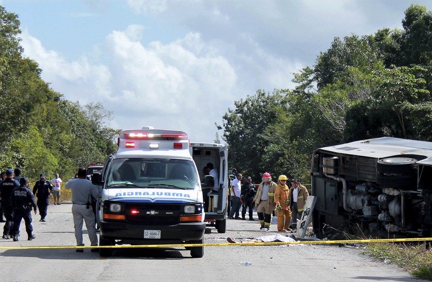 The lifeless body of a passenger lies next to an overturned bus, as ambulances, firefighters and police stand by in Mahahual, Quintana Roo state, Mexico, Tuesday, Dec. 19, 2017. The bus carrying cruis ...