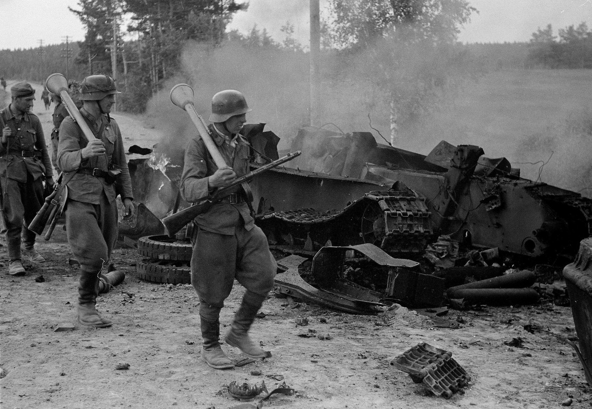 Finnische Soldaten passieren einen zerstörten sowjetischen T-34.