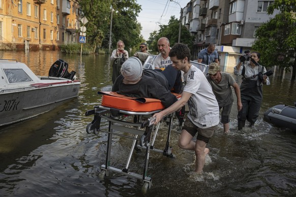 Volunteers drag a woman on a stretcher as she was evacuated from a flooded neighborhood on the left bank of the Dnipro River, in Kherson, Ukraine, Friday, June 9, 2023. In Ukraine, the governor of the Khers…