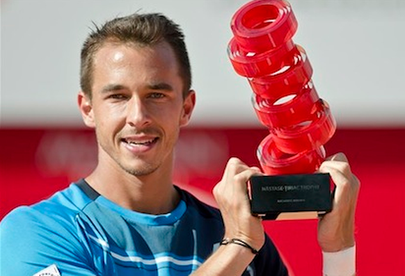 Man nehme sechs rote Klebebandrollen. Fertig ist der Pokal. Lukas Rosol hat trotzdem Freude an den kleinen Dingen des Lebens. Pokal: ATP-Turnier in Bukarest.