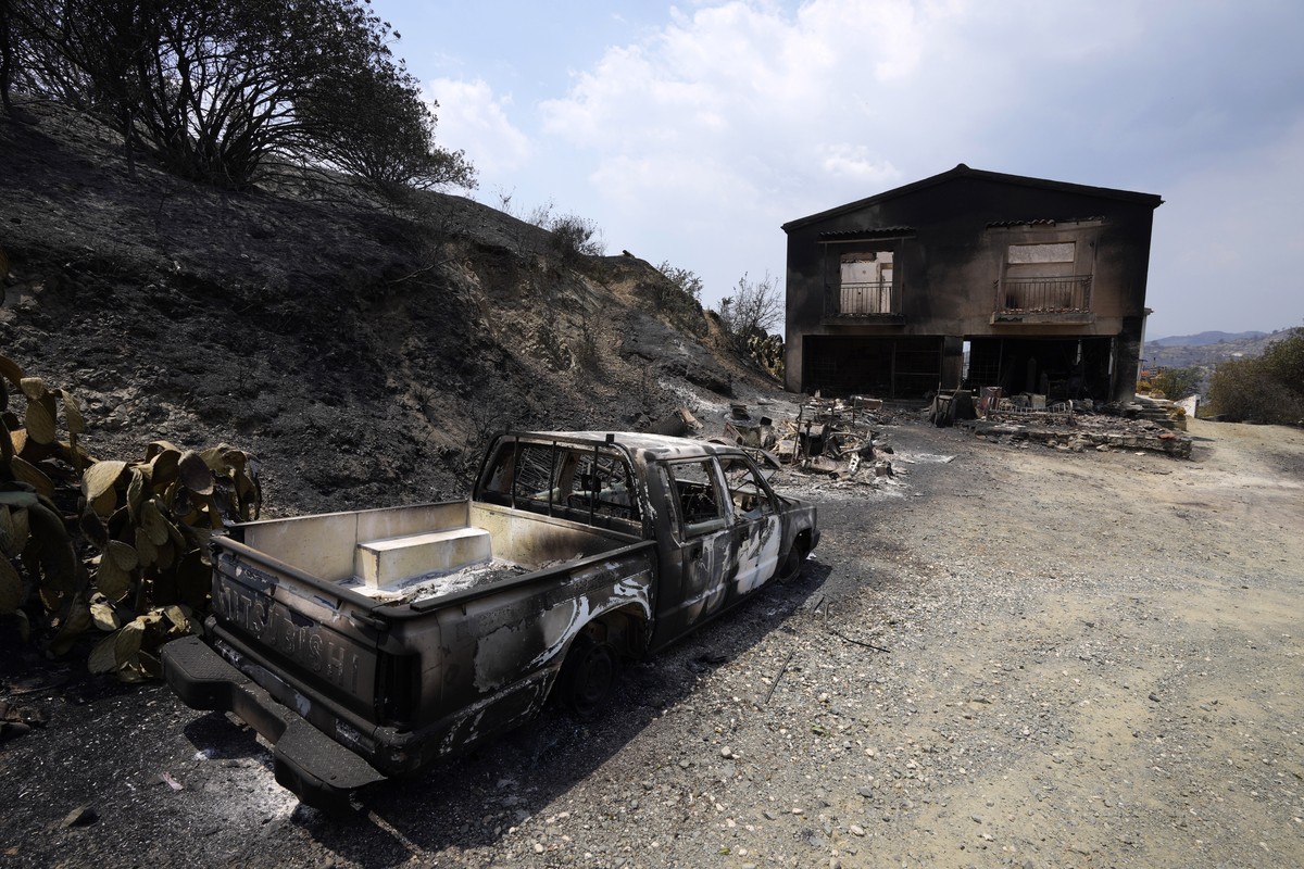 A burned car is seen outside a damaged house on Troodos mountain, in Ora village, southwestern Cyprus, Sunday, July 4, 2021. Cyprus search crews discovered the bodies of four people outside a fire-swe ...