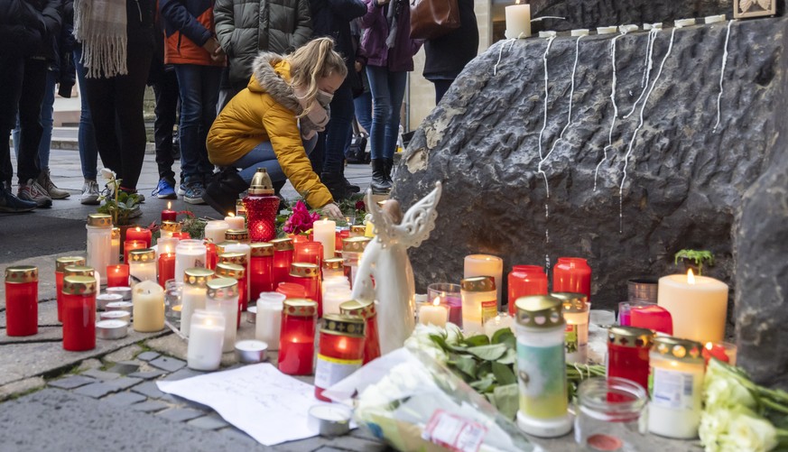 epa08856443 People stand mourning in front of burning candles at Porta Nigra in the aftermath of a fatal incident in Trier, Germany, 02 December 2020. According to reports, five people died, including ...