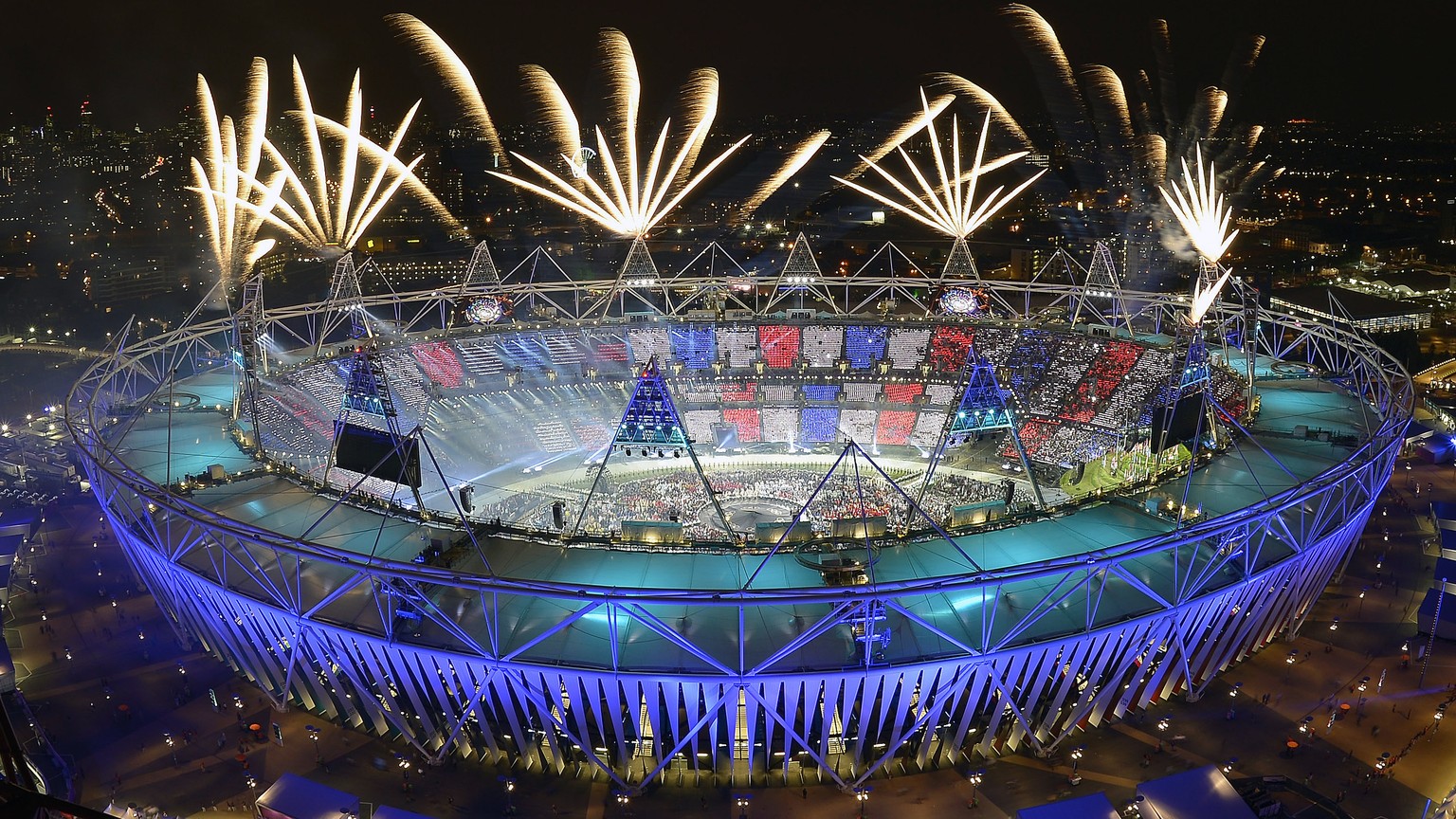 FILE - In this July 28, 2012, file photo, fireworks illuminate the sky over the Olympic Stadium during Opening Ceremonies at the 2012 Summer Olympics in London. Always splashy affairs, the parade of a ...