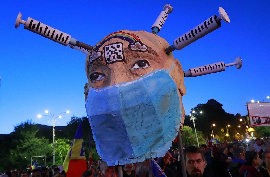 epa09502574 Romanian anti-vaccine activists display a huge metaphoric human head with syringes tucked into the scalp while attending a protest against new measures ordered by the Romanian government d ...