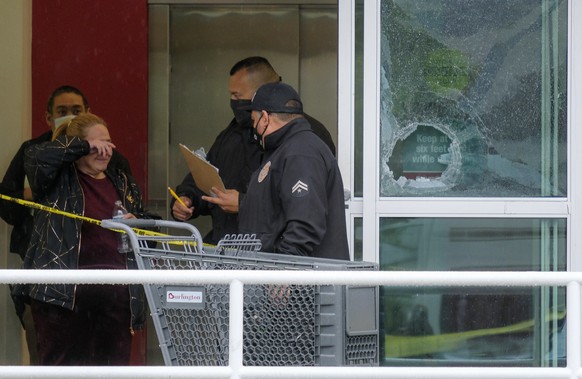 A woman wipes her eye as police officers investigate the scene where two people were struck by gunfire in a shooting at a Burlington store as part of a chain formerly known as Burlington Coat Factory  ...
