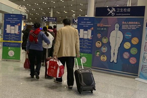 In this Jan. 13, 2020, photo, travelers pass by a health checkpoint before entering immigration at the international airport in Beijing. The possibility that a new virus in central China could spread  ...