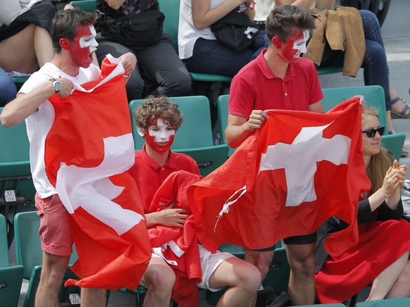 Supporters of Timea Bacsinszky of Switzerland wave Swiss flags as she plays her fourth round match against Venus Williams of the U.S. at the French Open tennis tournament at the Roland Garros stadium, ...