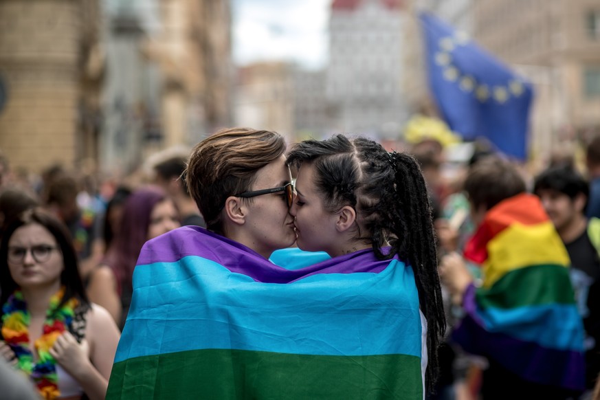 epa06943206 Two women wrapped in the rainbow flag kiss each other during the Prague Pride parade in downtown Prague, Czech Republic, 11 August 2018. Several thousands of people attended the 8th Prague ...