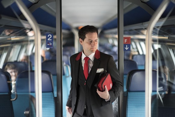 A train conductor of the Swiss Federal Railways checks passenger's tickets on a train travelling from Zurich to Lucerne, Switzerland, on March 20, 2017. (KEYSTONE/Christian Beutler)