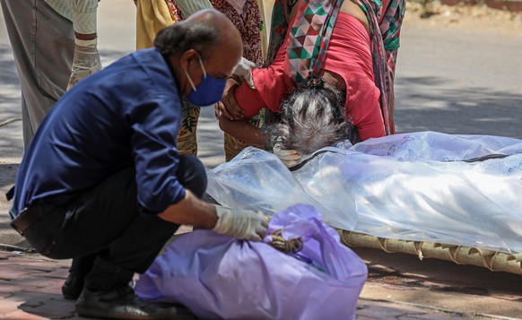 epa09191398 People mourn while they perform the last rites for their relatives who died with Covid-19 during their funeral at a cremation ground in Ahmedabad, India, 11 May 2021. Calls for Prime Minis ...