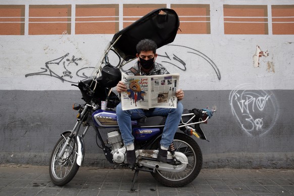 epa08803965 A man reads a copy of Iranian daily newspaper Sobhe Nou with a cartoon depicting US president Donald J Trump and a headline reading 'Go to hell gambler', in front of a newsstand in Tehran, Iran, 07 November 2020. According to local media reports, many Iranians are rooting for Democratic candidate Joe Biden.  EPA/ABEDIN TAHERKENAREH