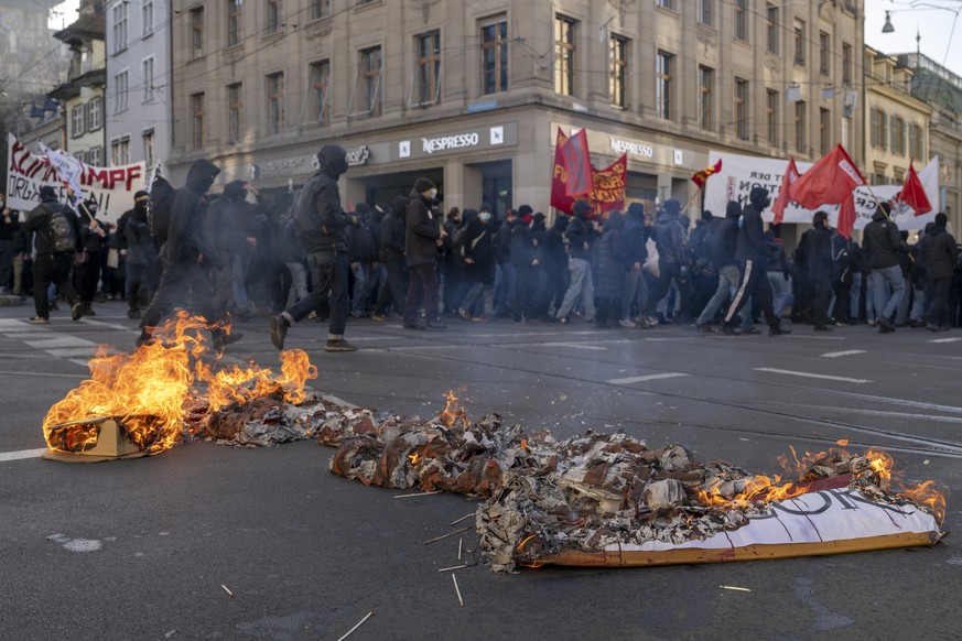 Vermummte Teilnehmer einer unbewilligten Klimadenonstration durchbrechen eine Polizeiblockade in Basel, am Samstag, 11. Februar 2023. (KEYSTONE/Georgios Kefalas)