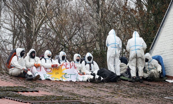 epa10401598 Activists wearing personal protective equipment (PPE) sit on the roof of one of the occupied houses in the village of Luetzerath, Germany, 12 January 2023. The village of Luetzerath in Nor ...