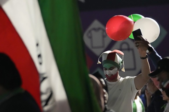 A soccer fan with his face painted with the colors of the Iran flag carry balloons ahead of the World Cup group B soccer match between Iran and the United States at the Al Thumama Stadium in Doha, Qat ...