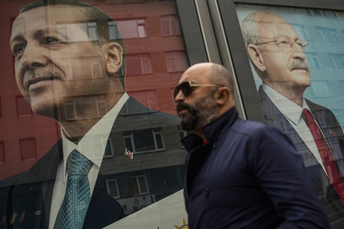 A man walks past election campaign billboards of Turkish President and People's Alliance's presidential candidate Recep Tayyip Erdogan, left, and CHP party leader and Nation Alliance's  ...