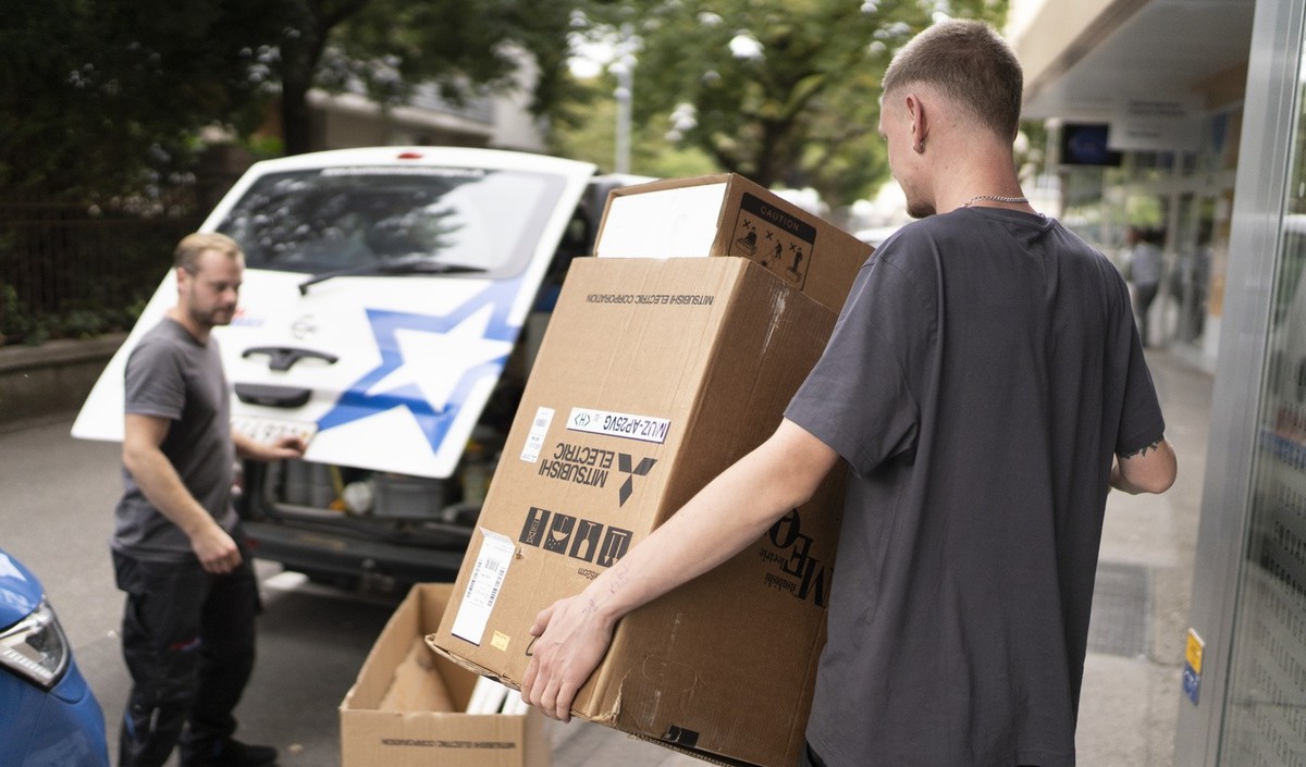 Alain, Lehrling im Kaeltesystem-Monteur, traegt den leeren Karton der Klimaanlage in den Lieferwagen, fotografiert am Donnerstag, 31. August 2023 in Biel. Martin, Kaeltesystem-Monteur bei der Firma Bu ...