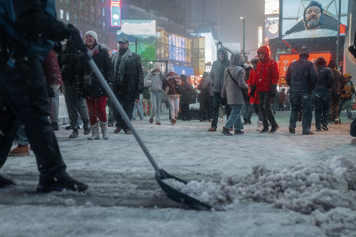 epa12613655 A person shovels snow in Times Square during a winter storm in New York, New York, USA, 26 December 2025. A weather emergency was declared as up to 11 inches of snow was forecast, and hund ...
