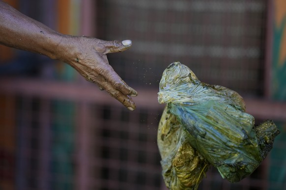 A worker throws a plastic bag as he seperates garbage at a recycling facility in Malabon, Philippines on Monday Feb. 13, 2023. Food waste emits methane as it breaks down and rots. Waste pickers are he ...