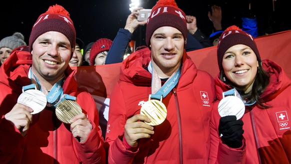 Silver and Bronze medals, Beat Feuz of Switzerland, left, Gold medal, Dario Cologna of Switzerland, center, and Silver medal, Wendy Holdener of Switzerland, right, celebrate at the House of Switzerlan ...