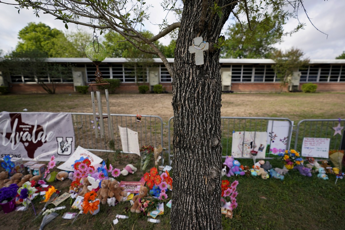A cross hangs on a tree at Robb Elementary School where a memorial has been created to honor the victims killed in the recent school shooting, Friday, June 3, 2022, in Uvalde, Texas. Two teachers and  ...