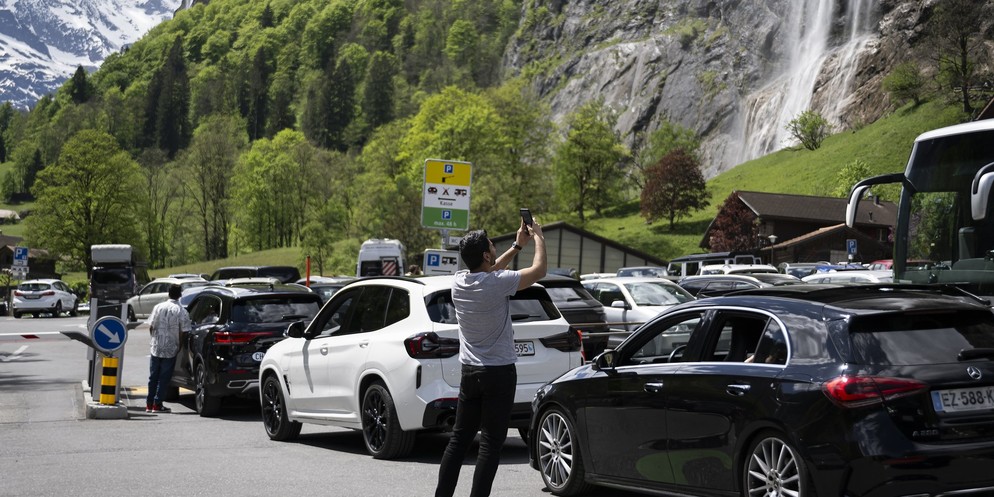 Touristen warten mit ihren Autos auf freie Parkplätze beim Parkplatz der Kirche in Lauterbrunnen.