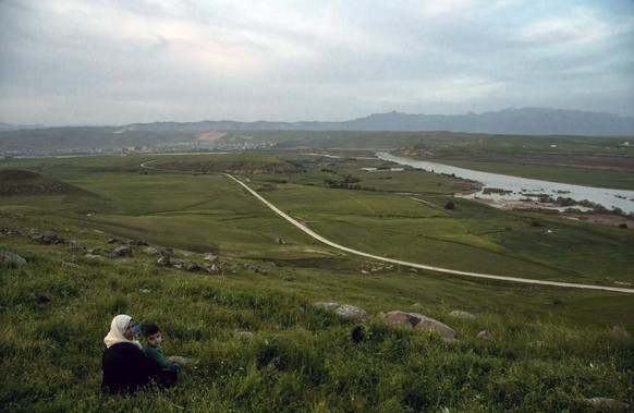 FILE - In this file photo dated Wednesday, May 1, 2019, a woman and child sit on a hill overlooking the Euphrates River as families picnic on May Day, in Derik, Syria. Turkey wants to establish a safe ...