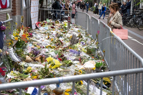 epa09346247 People mourn at the flowers for Peter R. de Vries at the back of the Lange Leidsedwarsstraat in the center Amsterdam, The Netherlands, 15 July 2021. According to a statement of the family, ...