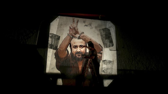 epa05990551 A Palestinian paints an image depicting Palestinian leader and prominent prisoner Marwan Barghouti on a wall on the streets of Gaza City, 25 May 2017. More the 1,500 Palestinian prisoners  ...