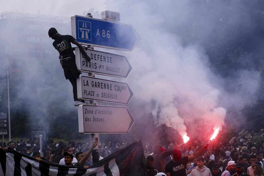 epaselect epa10717471 A person climbs a traffic sign as others hold flares during a march in the memory of 17-year-old Nahel, who was killed by French Police in Nanterre, near Paris, France, 29 June 2 ...