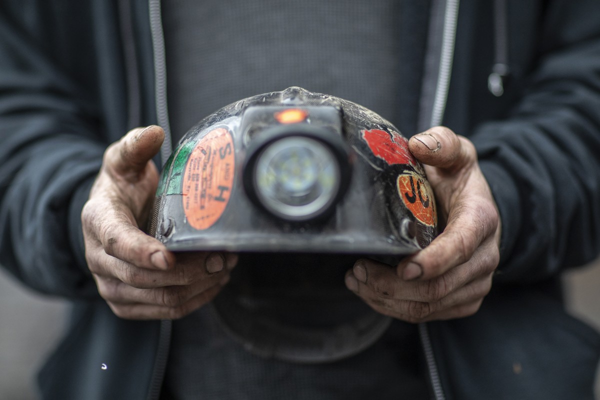 In this Tuesday, Jan. 14, 2020 photo, Kenny Collins, an employee of Quest Energy, holds his mining helmet near railroad tracks where miners, who say they haven't been paid in nearly three weeks,  ...