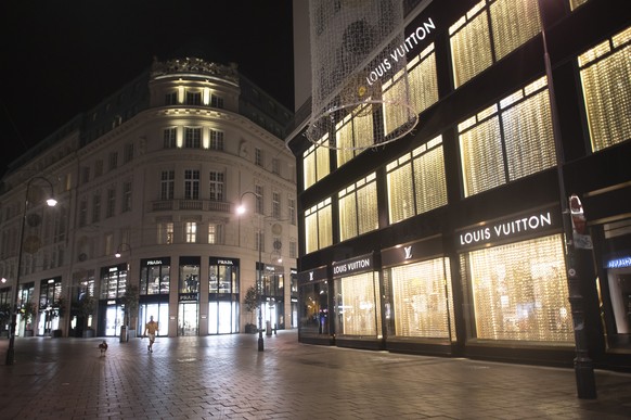 epa08796766 A man walks his dog on an empty shopping street during the night-time curfew of the the Austrian lockdown on the evening after multiple shootings in the first district of Vienna, Austria,  ...