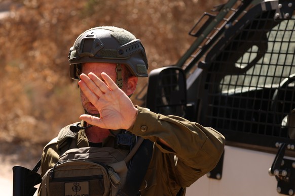 epa13163901 An Israeli soldier blocks a road as Israeli settlers besiege a Palestinian home for the fourth consecutive day in the town of Qusra, south of Nablus, 12 August 2026. According to the Wafa  ...