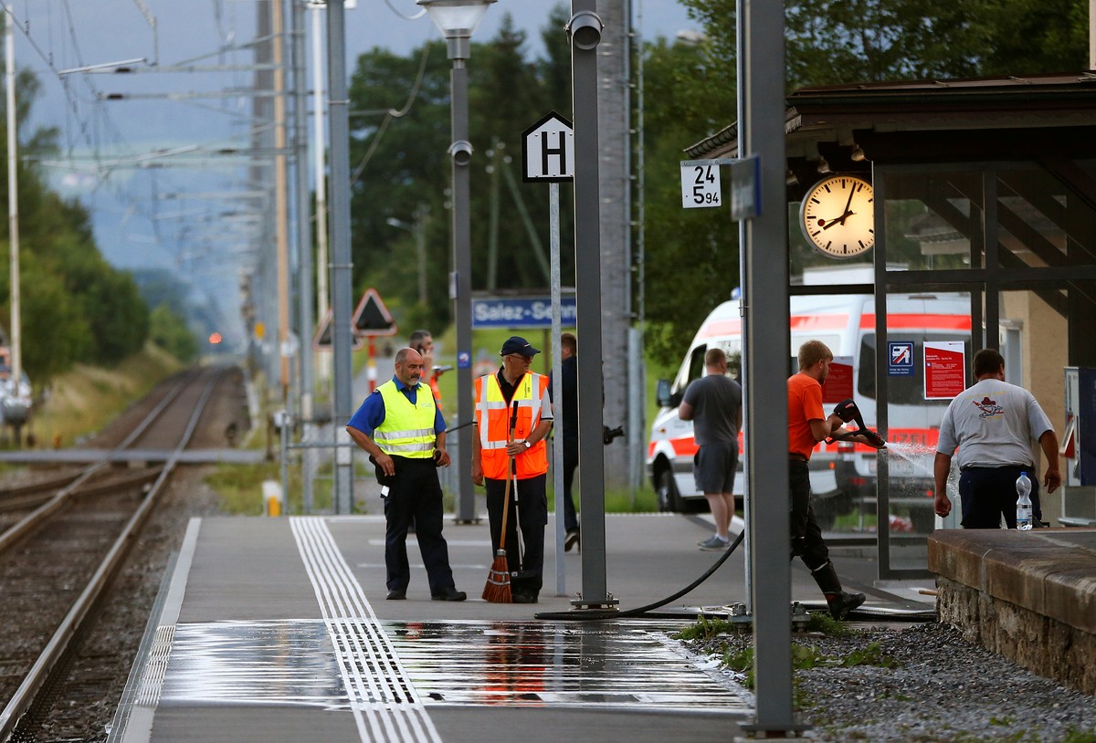 A Swiss police officer stands near workers cleaning a platform after a 27-year-old Swiss man's attack on a Swiss train at the railway station in the town of Salez, Switzerland August 13, 2016. RE ...