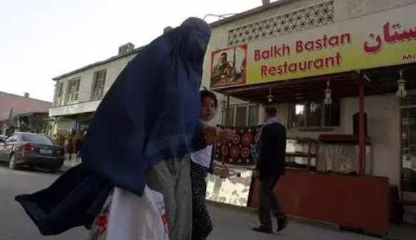 An Afghan woman clad in burqa and her daughter walks past a restaurant built inside part of the only synagogue building in Kabul, June 1, 2011