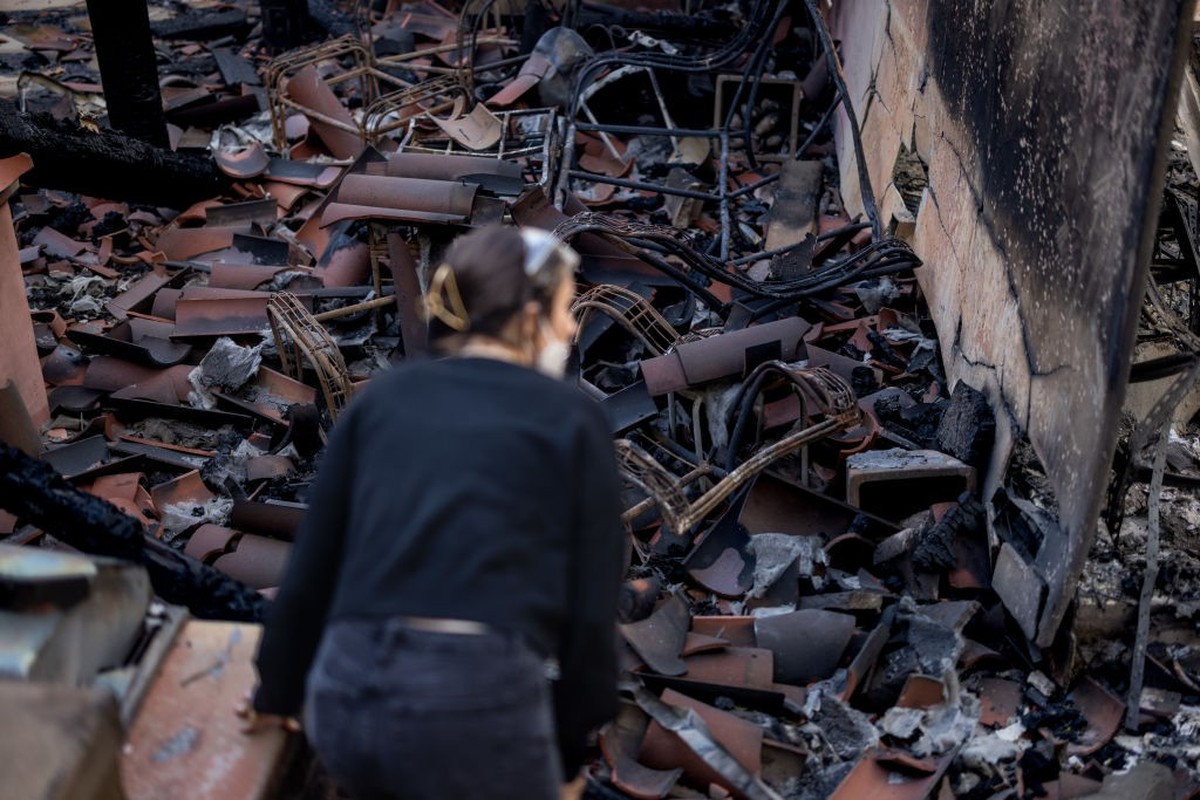 PACIFIC PALISADES, CALIFORNIA - JANUARY 09: Sara Rygiel checks her parent's destroyed house during the Palisades Fire at Whitfield Avenue on January 9, 2025, in the Pacific Palisades community of ...