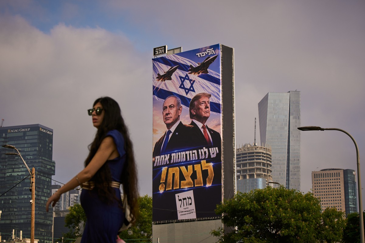 A woman walks past a Likud Party campaign billboard featuring U.S. President Donald Trump and Israeli Prime Minister Benjamin Netanyahu, with a Hebrew message reading, "We have one opportunity to ...