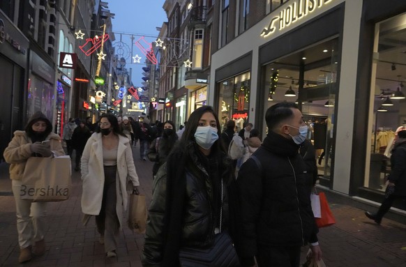 People walk down a street in Amsterdam, the Netherlands, Saturday, Dec. 18, 2021. Dutch government ministers are meeting Saturday to discuss advice from a panel of experts who are reportedly advising  ...