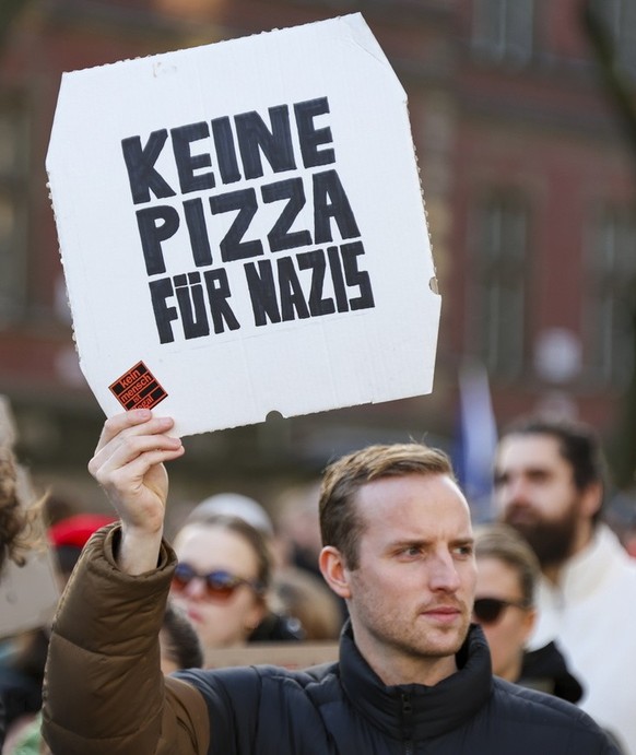 epa11108540 A protester holds a sign reading &amp;#x201a;no pizza for nazis&amp;#x2018; in front of Cologne Cathedral, during a demonstration against the far-right Alternative for Germany (AfD) party  ...
