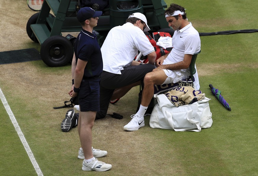 Roger Federer of Switzerland receives medical attention during a break in his men&#039;s semifinal singles match against Milos Raonic of Canada on day twelve of the Wimbledon Tennis Championships in L ...